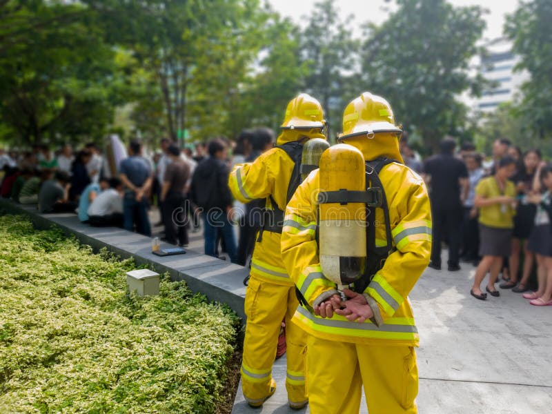 Selecione o foco de sapadores-bombeiros traseiros no terno amarelo com um tanque de oxigênio na parte traseira Os sapadores-bombe fotografia de stock Selecione o foco de sapadores-bombeiros traseiros no terno amarelo com um tanque de oxigênio na parte traseira Os sapadores-bombe fotografia de stock