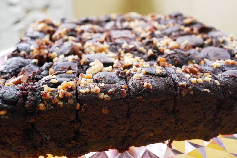 Selected focused on the chocolate cake. Rectangular in shape. Crushed almonds are sprinkled on it. Has been cut into small cubes to make it easier to eat.