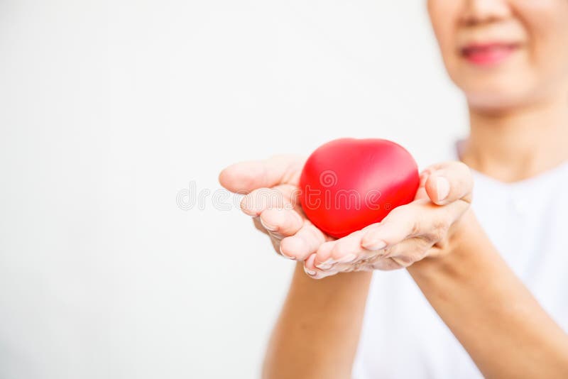 Selectieve nadruk van rood die hart door glimlachende vrouwelijke verpleegster ` s beide hand wordt gehouden, die gevend al inspa royalty-vrije stock afbeelding Selectieve nadruk van rood die hart door glimlachende vrouwelijke verpleegster ` s beide hand wordt gehouden, die gevend al inspa royalty-vrije stock afbeelding