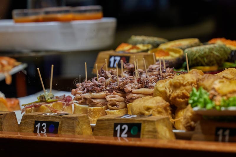 Selection of traditional Basque pinchos, arranged on baguette slices with different toppings stock image