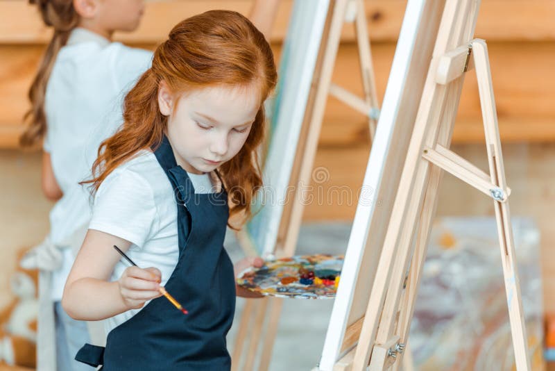 Selective Focus Of Cute Kid Standing And Painting In Art School Stock