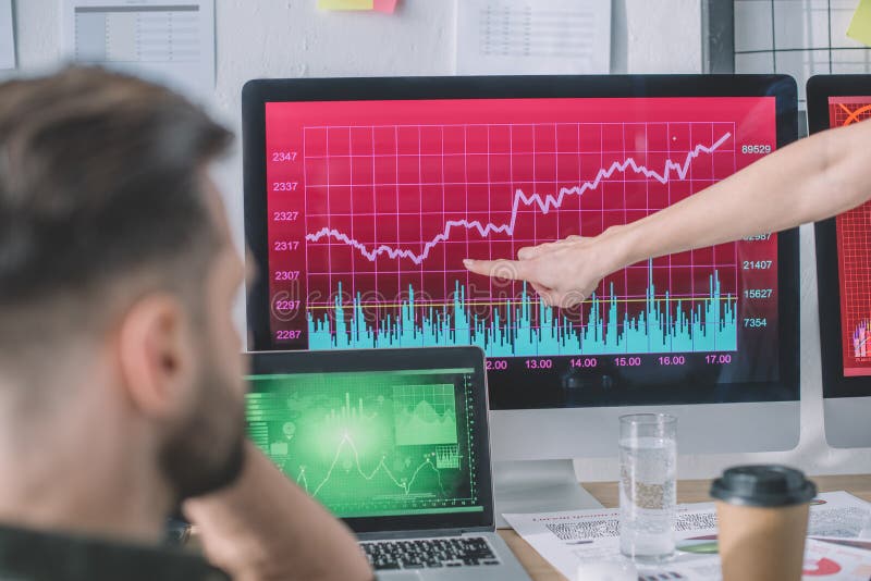 Selective focus of data analyst pointing at chart on computer monitor to colleague royalty free stock photos