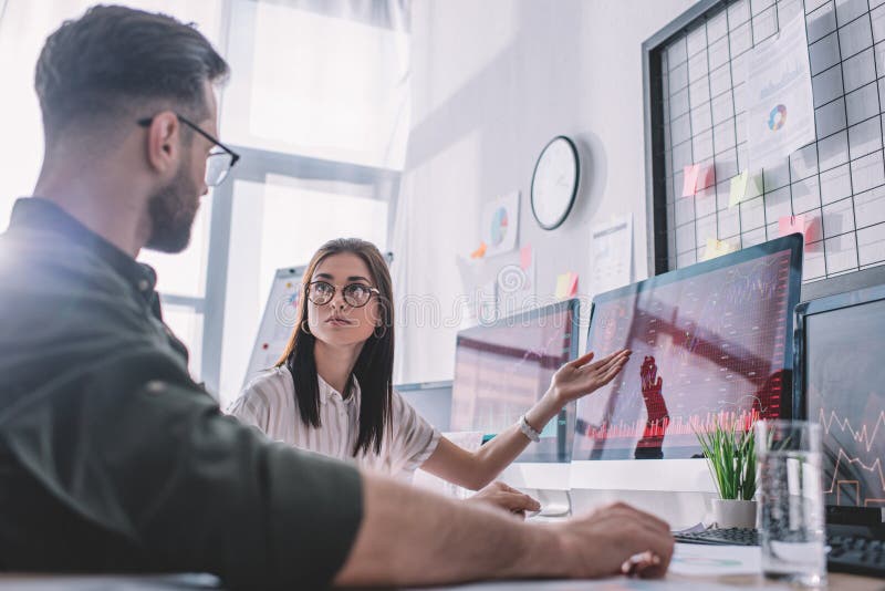 Selective focus of data analyst pointing with hand on computer monitor to colleague stock photos