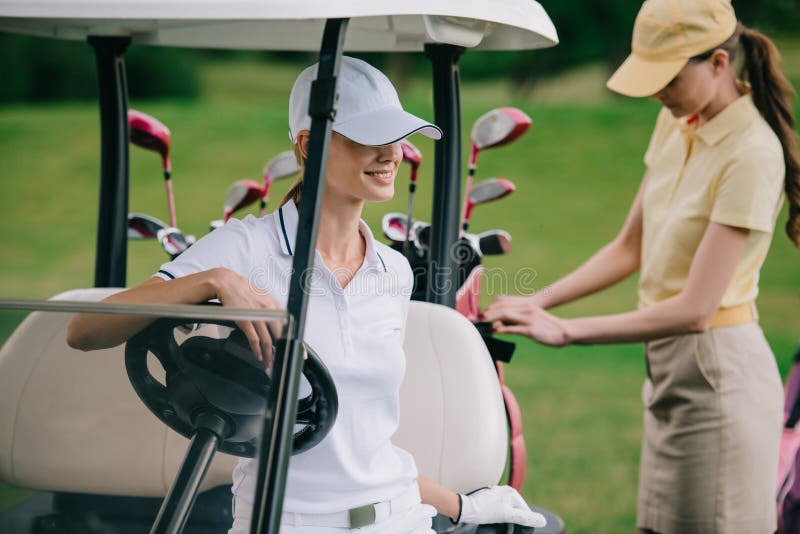 Selective Focus of Female Golf Players in Caps at Golf Cart Stock Photo