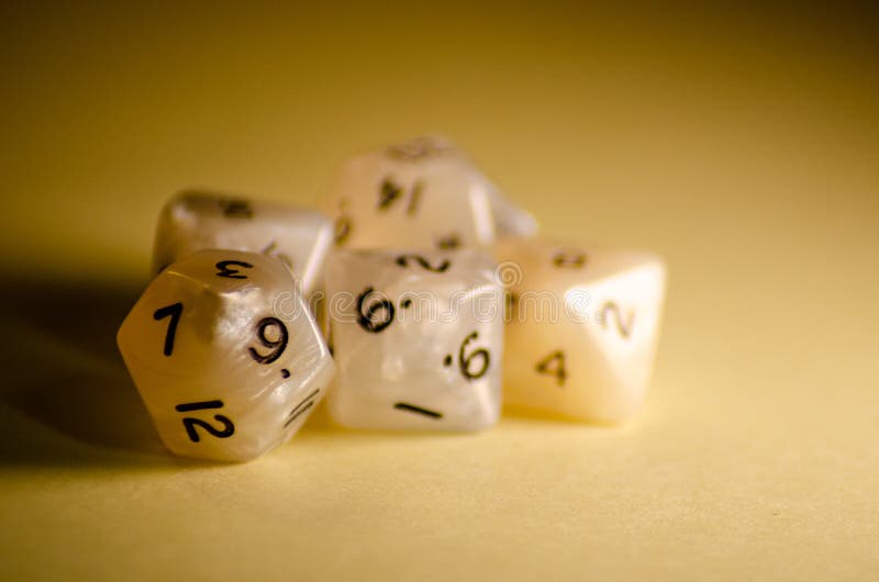 Selective focus, five 12-sided white dice on yellow background dice for role-playing games stock photo