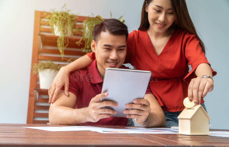 Selective focus of golden coin. Happy Asian couples smiling Because it is profitable from investment And have savings for buying a royalty free stock photo Selective focus of golden coin. Happy Asian couples smiling Because it is profitable from investment And have savings for buying a royalty free stock photo