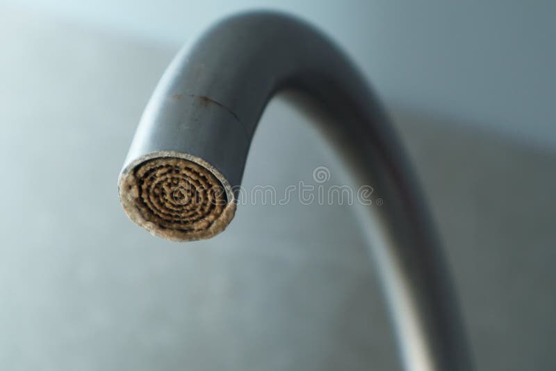 Selective focus on hard water deposit. Dirty faucet aerator with limescale, calcified shower water tap with lime scale in the royalty free stock images