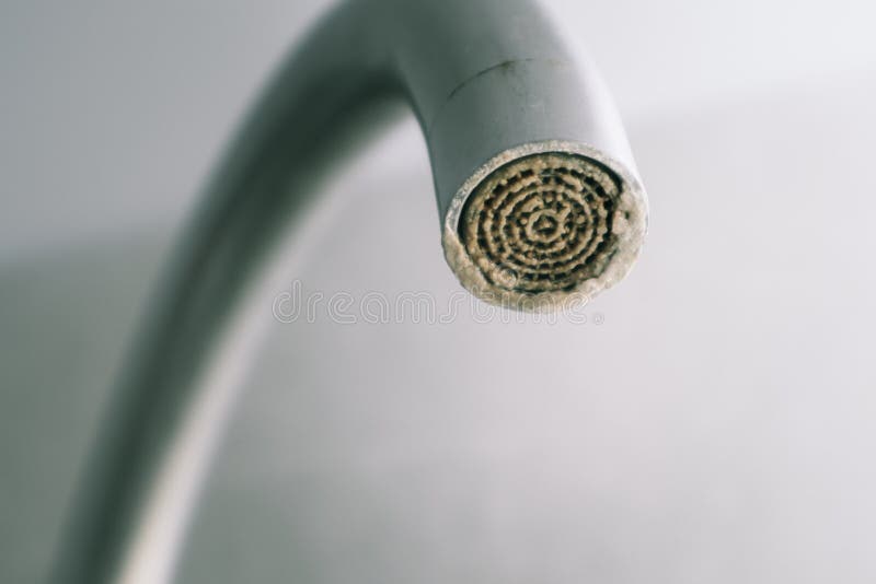 Selective focus on hard water deposit. Dirty faucet aerator with limescale, calcified shower water tap with lime scale in the royalty free stock photo