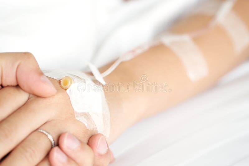 Selectivo concentrarse sobre el hombre mano posesión una mujer pacientes mano recepción salado de acuerdo a intravenoso inyección sobre el una cama en a apoyo su esposa.