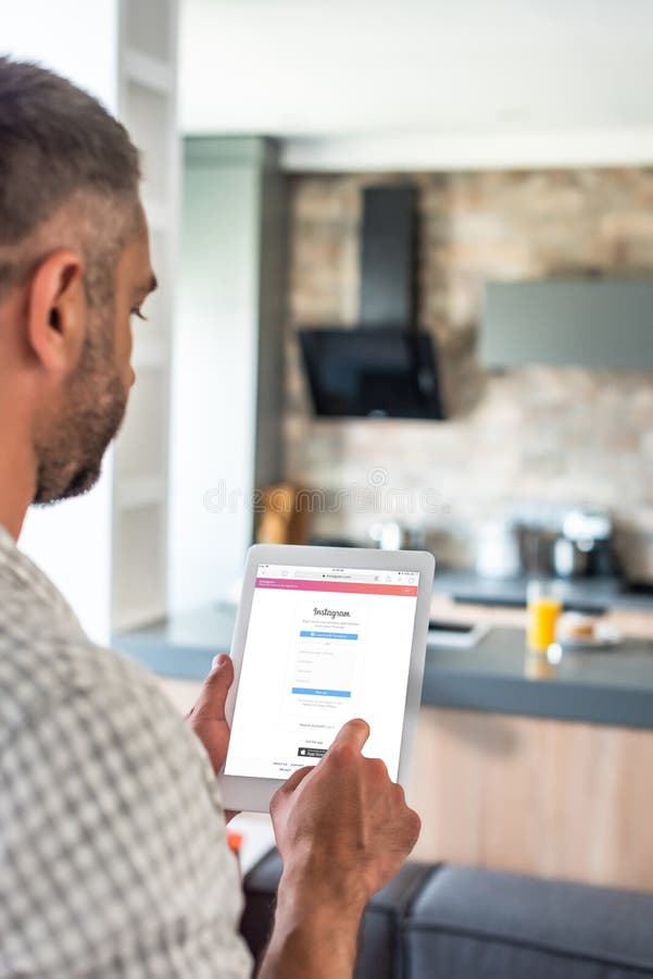 selective focus of man using digital tablet with instagram logo on screen in kitchen