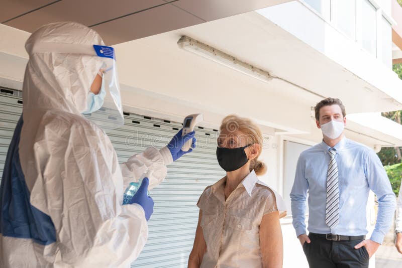 Selective Focus. A medical worker in hazmat suit using thermometer to check the employee