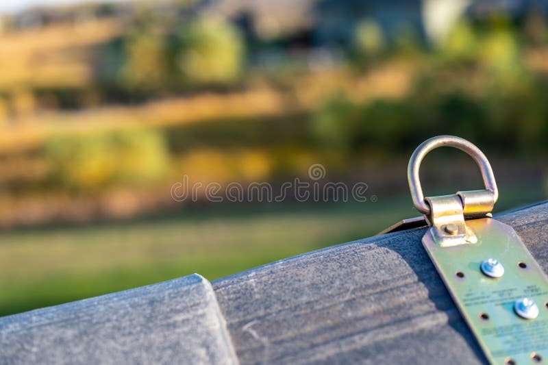 Selective focus on a metal temporary anchor installed on the peak of a roof for fall protection.