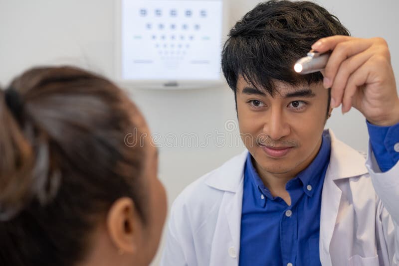 Selective Focus at Optometrist Face. while Doctor Using Penlight and