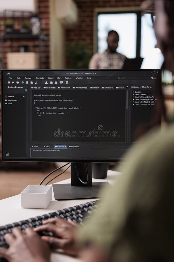 Selective focus on programmer typing code on computer keyboard while roommate is relaxing stock image