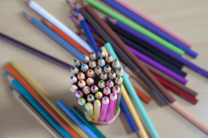 Selective focus shot of a bundle of colored pencils next to a few more on a wooden surface stock photography