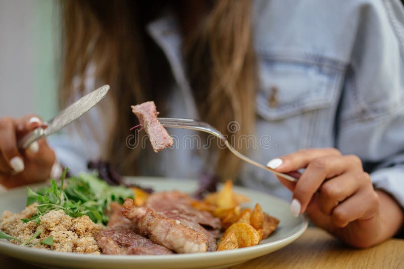Selective Focus Shot of a Female Eating a Dish with Steak and Potato