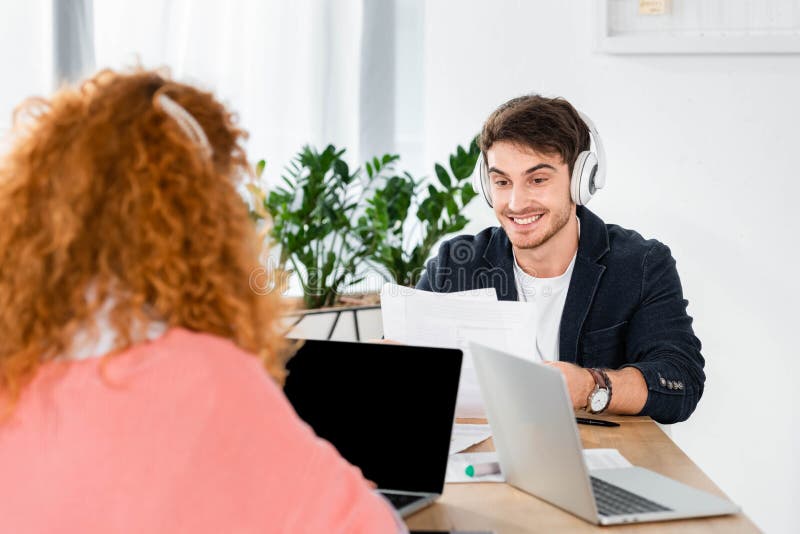 Focus of smiling and handsome man in headphones using laptop stock photography