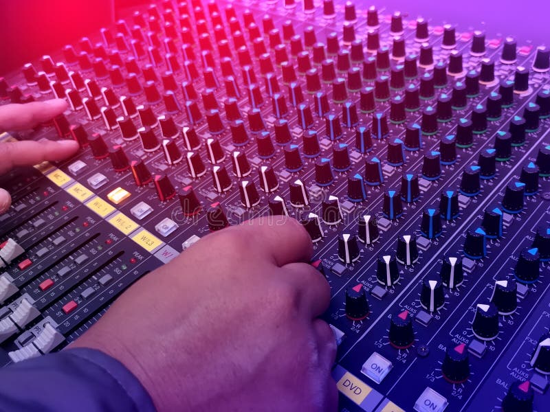 Selective focus of the sound mixer with hand is adjusting sound. Hand pressing the button on the audio mixer royalty free stock photo