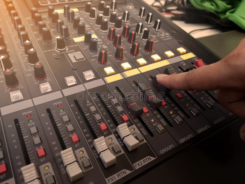 Selective focus of the sound mixer with hand is adjusting sound. Hand pressing the button on the audio mixer royalty free stock images