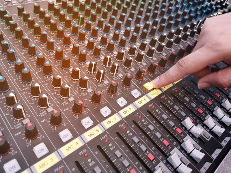 Selective focus of the sound mixer with hand is adjusting sound. Hand pressing the button on the audio mixer stock photography