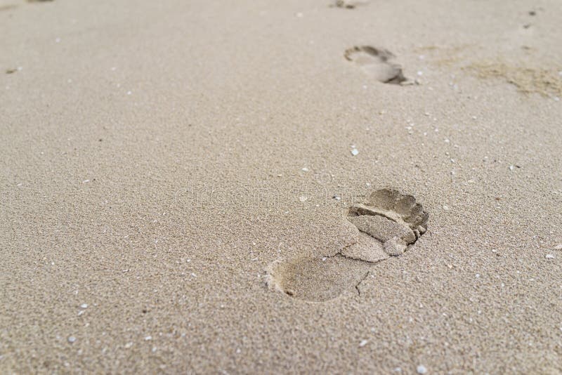 Selekcyjna ostrość na dużym odcisku stopy na piasku jako życie podróży przeciw
