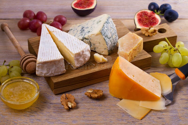 Selezione del formaggio su fondo rustico di legno Vassoio del formaggio con differenti formaggi, serviti con l'uva, i fichi, i da fotografia stock
