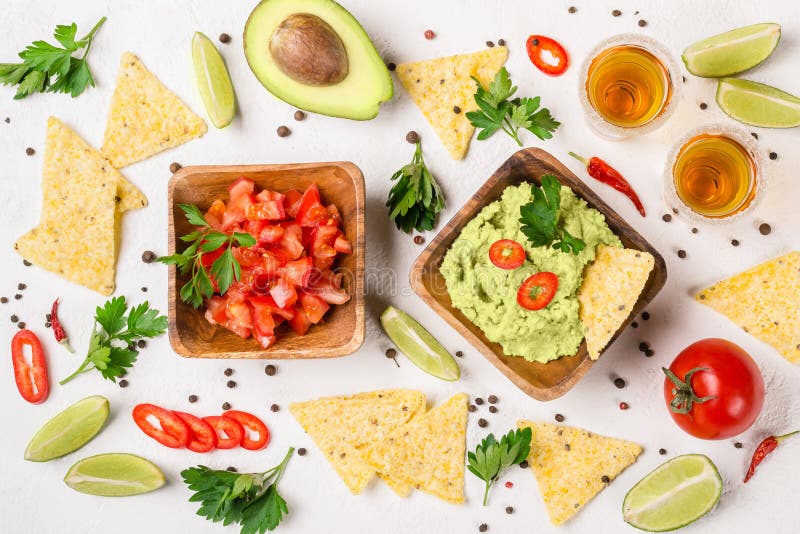 Selezione messicana del partito dell'alimento: guacamole della salsa, salsa, patatine fritte e colpi di tequila con calce fotografia stock Selezione messicana del partito dell'alimento: guacamole della salsa, salsa, patatine fritte e colpi di tequila con calce fotografia stock