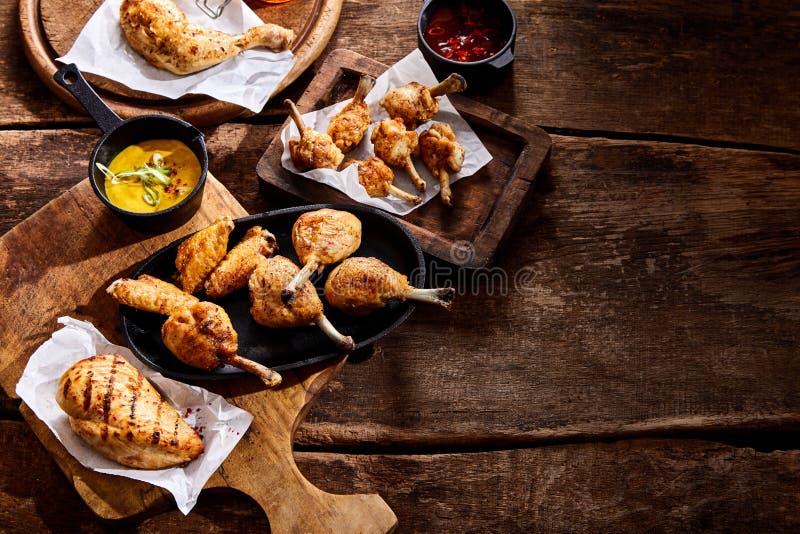 Selection of crispy grilled assorted chicken portions on old wooden trays on a rustic wood background view from above at a summer BBQ. Selection of crispy grilled assorted chicken portions on old wooden trays on a rustic wood background view from above at a summer BBQ