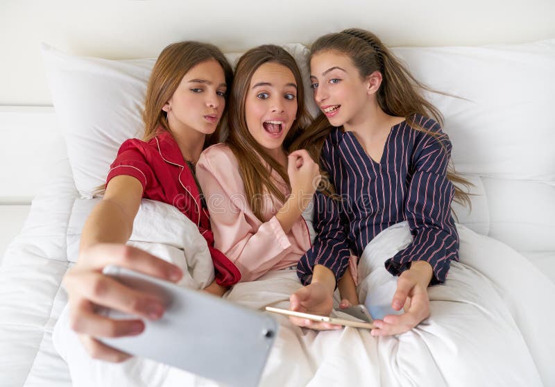 Pajama party best friend girls selfie at bed with tablet and smartphone. Pajama party best friend girls selfie at bed with tablet and smartphone