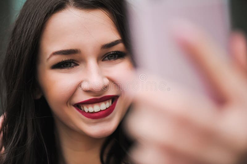 Selfie de la toma de la chica joven de las manos con el teléfono en la calle de la ciudad del verano Concepto de la vida urbana fotografía de archivo Selfie de la toma de la chica joven de las manos con el teléfono en la calle de la ciudad del verano Concepto de la vida urbana fotografía de archivo