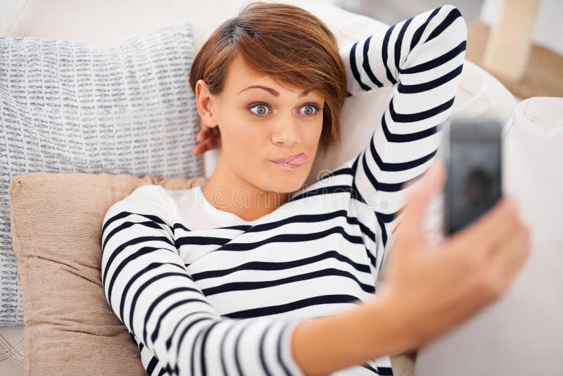 Selfie et drôle de femme ou se détendre sur canapé pour la communication stupide et les médias sociaux à la maison. jeune sur cana photos stock