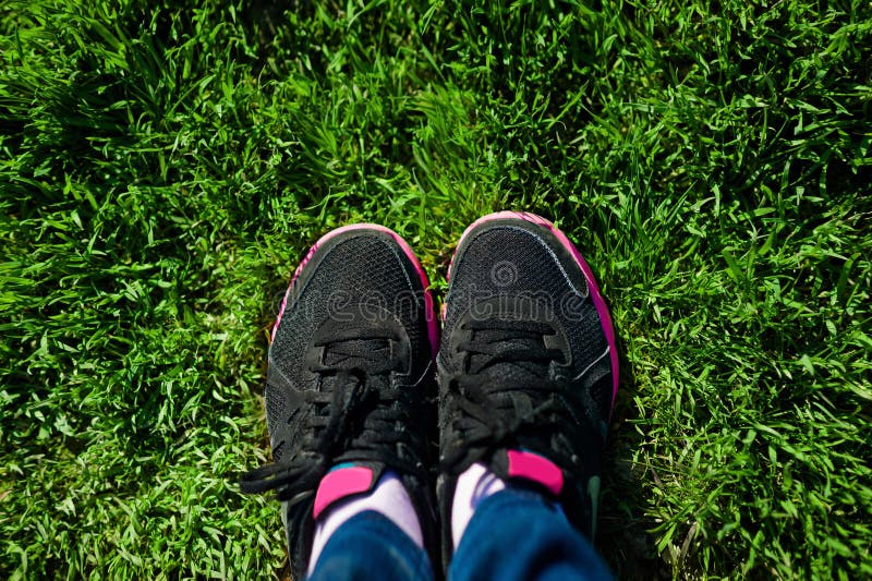 Selfie of female feet on black sneakers standing on green grass stock photos Selfie of female feet on black sneakers standing on green grass stock photos