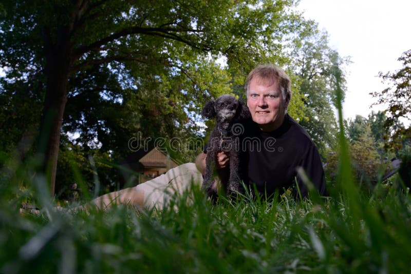 Selfie fatta da un uomo maturo, sorridendo e tenendo premuto il suo cane, un Barboncino.