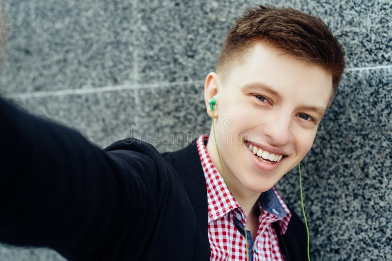 Selfie photo of attractive smiling young man in plaid shirt.