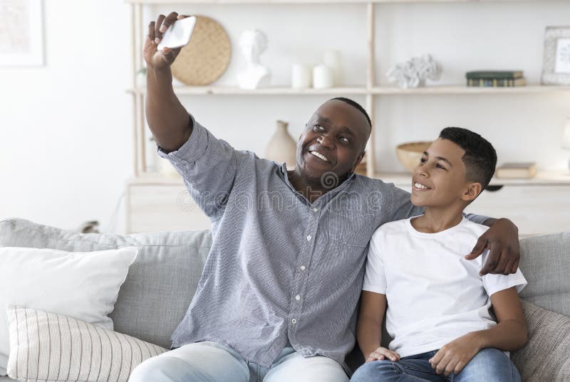 Selfie à la maison. Grand-père noir de sourire avec le petit-fils de la préadolescence ensemble de la photo image stock