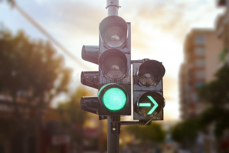 Semafor verde cu săgeată verde deschisă în oraș, în timp ce apusul permite ca mașina să se întoarcă la dreapta stock image