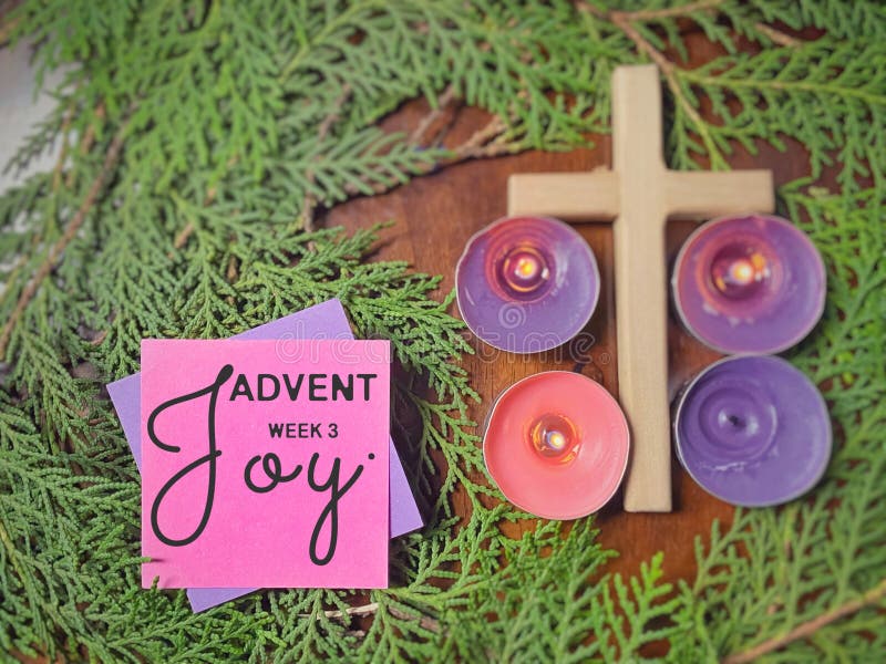 Advent week 3 joy text written on paper with cross, candles and wreath background. Christmas preparation. Advent season concept. Advent week 3 joy text written on paper with cross, candles and wreath background. Christmas preparation. Advent season concept.