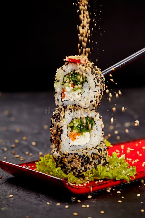Sementes de sésamo espalhadas na torre de sushi roll vegetariana fotos de stock