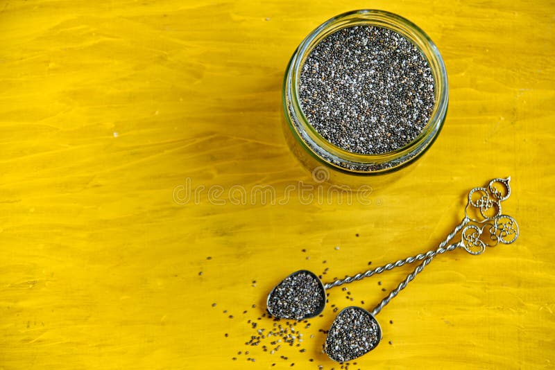 Sementes frescas do chia no fundo de madeira amarelo com espaço da cópia gratuita Colheres do vintage e frasco de vidro com chia fotos de stock Sementes frescas do chia no fundo de madeira amarelo com espaço da cópia gratuita Colheres do vintage e frasco de vidro com chia fotos de stock