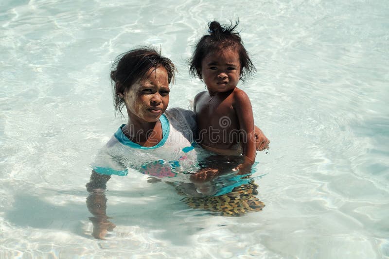Semporna, Sabah/Malesia - 5 giugno 2017: madre tribale del membro di bajau locale con il suo nuoto della figlia nel arou cristall immagini stock libere da diritti Semporna, Sabah/Malesia - 5 giugno 2017: madre tribale del membro di bajau locale con il suo nuoto della figlia nel arou cristall immagini stock libere da diritti