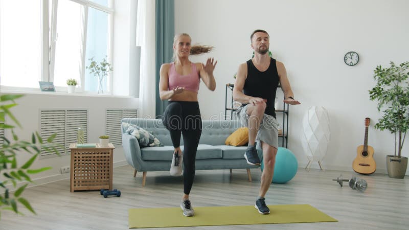 Sena rörelser för flicka och kille i sportkläder som hoppar över idrotten inomhus hemma arkivfilmer