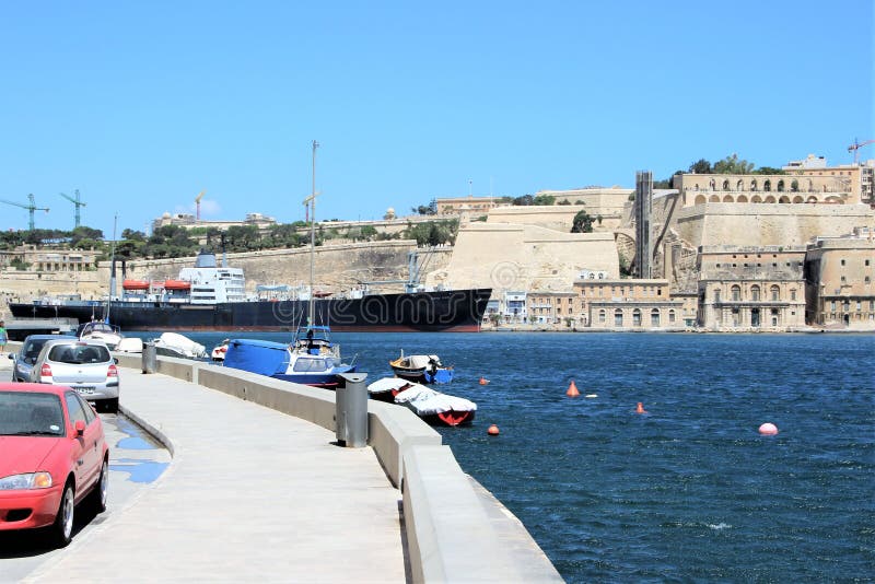 Senglea, Malta, em julho de 2015 Ideia das fortificações da capital da ilha no outro lado e no navio de carga de passagem fotos de stock Senglea, Malta, em julho de 2015 Ideia das fortificações da capital da ilha no outro lado e no navio de carga de passagem fotos de stock