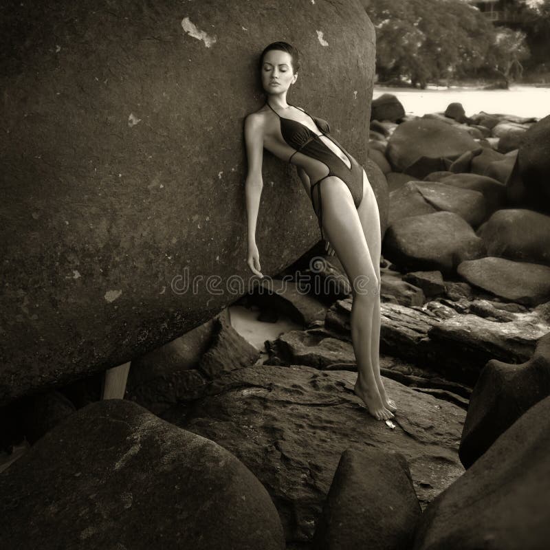 Beautiful elegant lady with a huge boulder on the seashore. Beautiful elegant lady with a huge boulder on the seashore