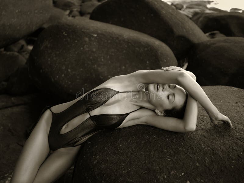 Beautiful elegant lady with a huge boulder on the seashore. Beautiful elegant lady with a huge boulder on the seashore