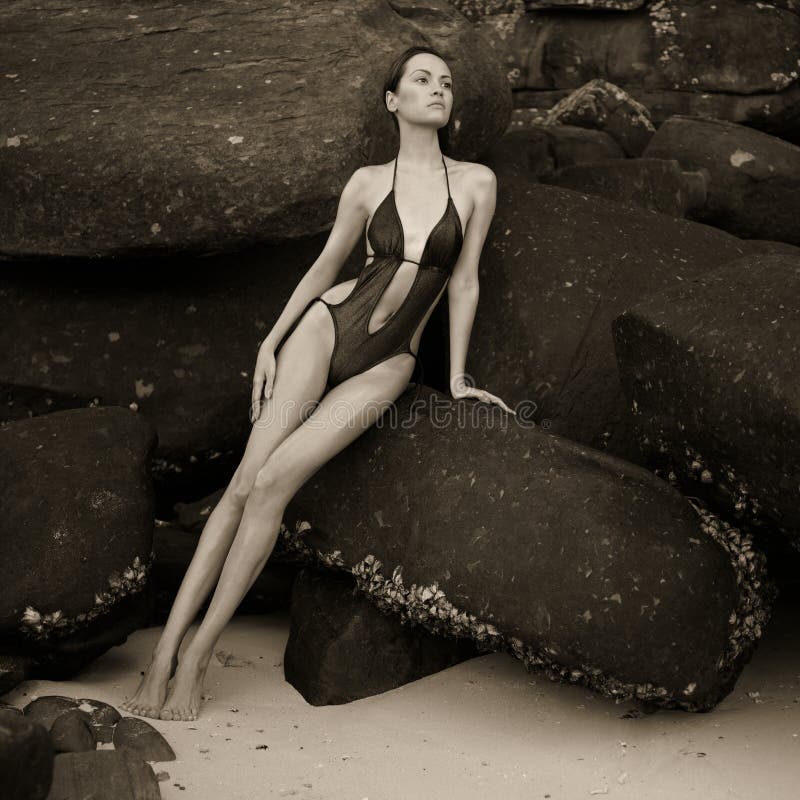 Beautiful elegant lady with a huge boulder on the seashore. Beautiful elegant lady with a huge boulder on the seashore