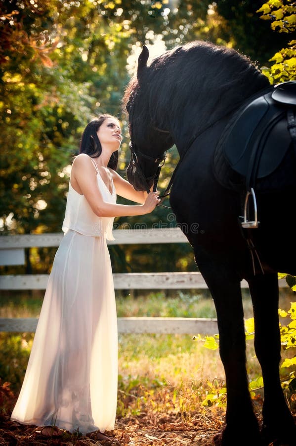 Senhora elegante com o vestido nupcial branco perto do cavalo marrom na natureza Jovem mulher bonita em um vestido longo que leva fotos de stock Senhora elegante com o vestido nupcial branco perto do cavalo marrom na natureza Jovem mulher bonita em um vestido longo que leva fotos de stock