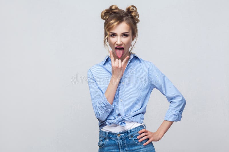 A senhora engraçada que olha a câmera com rocha canta e tongue para fora imagens de stock A senhora engraçada que olha a câmera com rocha canta e tongue para fora imagens de stock