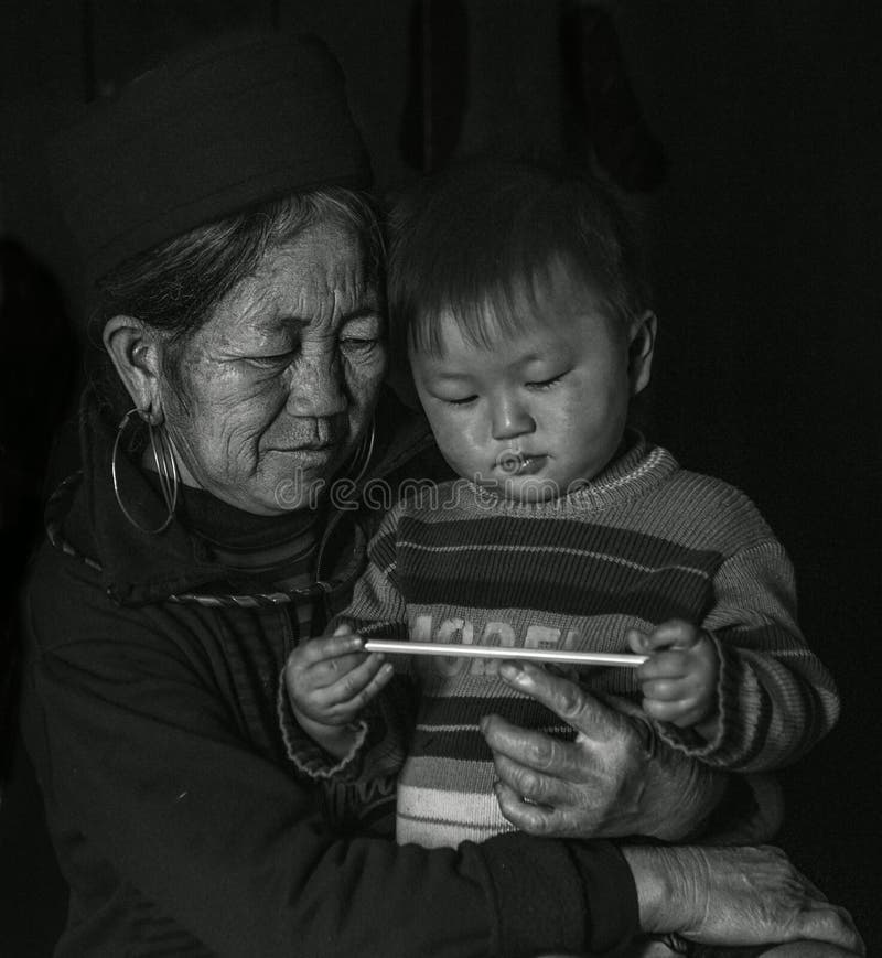 Senhora idosa do tribo de Hmong que guarda seu neto em seus braços dentro de sua casa, Sapa Vietname imagens de stock royalty free Senhora idosa do tribo de Hmong que guarda seu neto em seus braços dentro de sua casa, Sapa Vietname imagens de stock royalty free