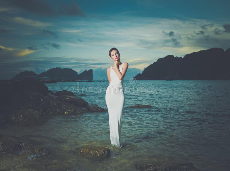 Beautiful lady in a white dress on a rocky shore. Beautiful lady in a white dress on a rocky shore