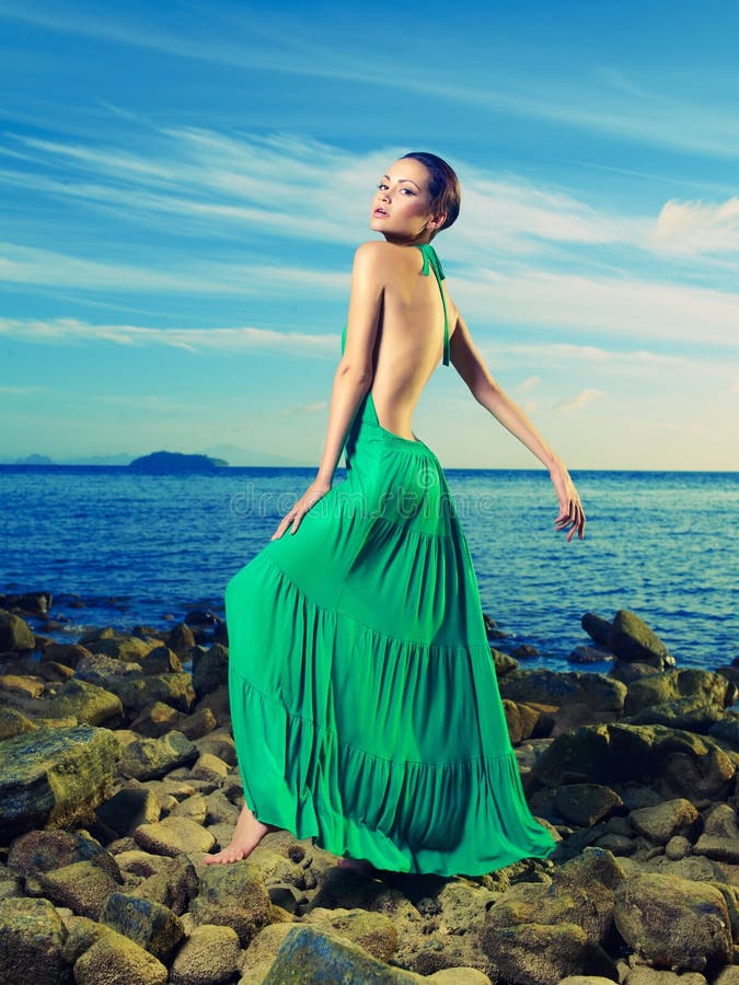 Beautiful lady in a green dress on a rocky shore. Beautiful lady in a green dress on a rocky shore